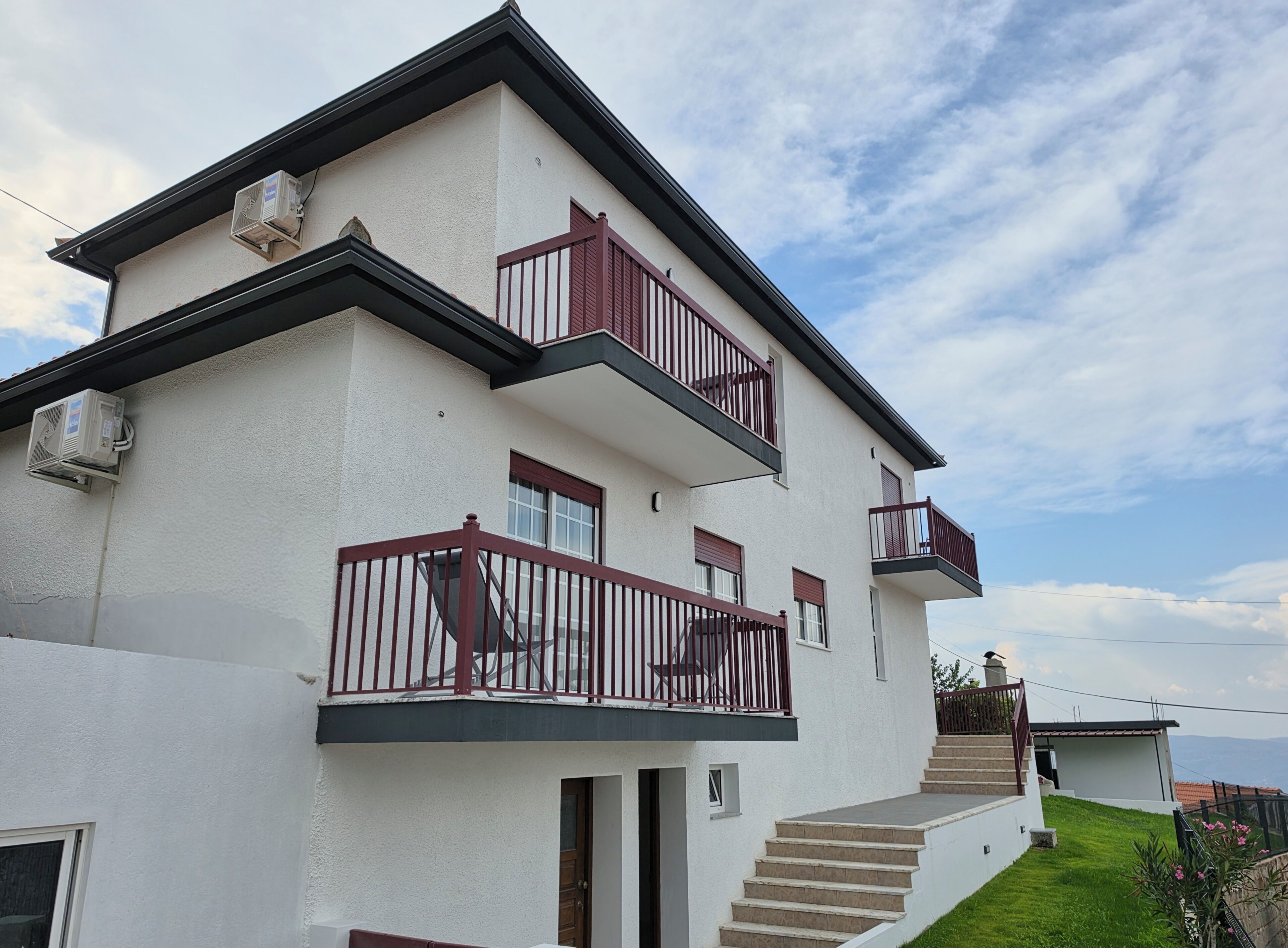 A two-story building with a balcony, a staircase, and a view of the landscape.