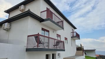 A two-story building with a balcony, a staircase, and a view of the landscape.