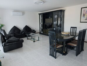 A living room with a black leather sofa, a glass coffee table, and a dining table with chairs. - Casa d'Avó (União das Freguesias de Felgueiras e Feirão)