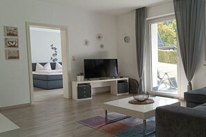 A modern living room with a flat-screen TV, a coffee table, and a sofa. - Holiday apartment with 1 bedroom (Schmallenberg-Grafschaft)