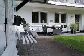 Een terras met buitenmeubilair, een tafel en stoelen.