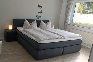 Een moderne slaapkamer met een groot bed, nachtlampjes en een raam met uitzicht.