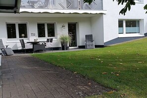 Un edifici blanc amb un pati empedrat, una taula amb caires i una planta en test.