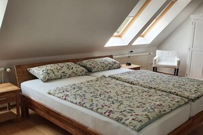 A bedroom with a wooden bed, two skylights, a radiator, and a white chair. - Holiday apartment Gries"scher Hof (Satjendorf)