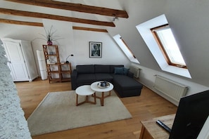 A living room with a sofa, a small table, a plant, and a picture on the wall. - Holiday apartment Gries"scher Hof (Satjendorf)