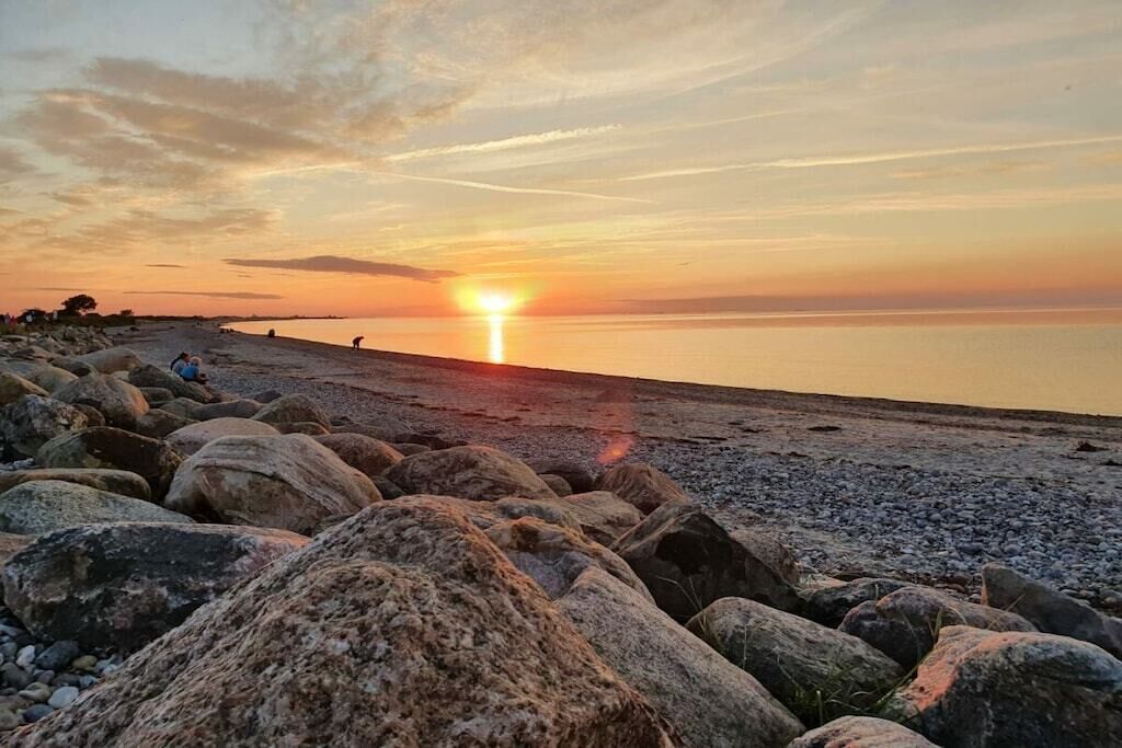 A rocky beach with the sun setting over the horizon.
