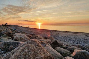 A rocky beach with the sun setting over the horizon. - Holiday apartment Gries"scher Hof (Satjendorf)