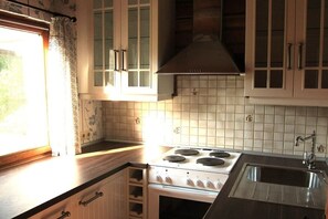 A kitchen with a stove, sink, and cabinets. - Heideblockhaus-Erika (Neuenkirchen)