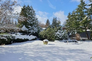 A snow-covered garden with trees and a wooden structure. - Heideblockhaus-Erika (Neuenkirchen)