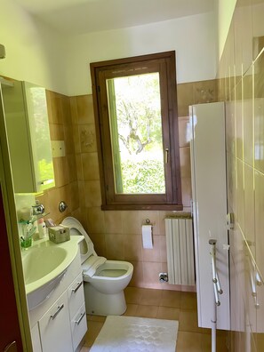 Une salle de bain équipée de toilettes, d’un lavabo, d’un miroir et d’une fenêtre.