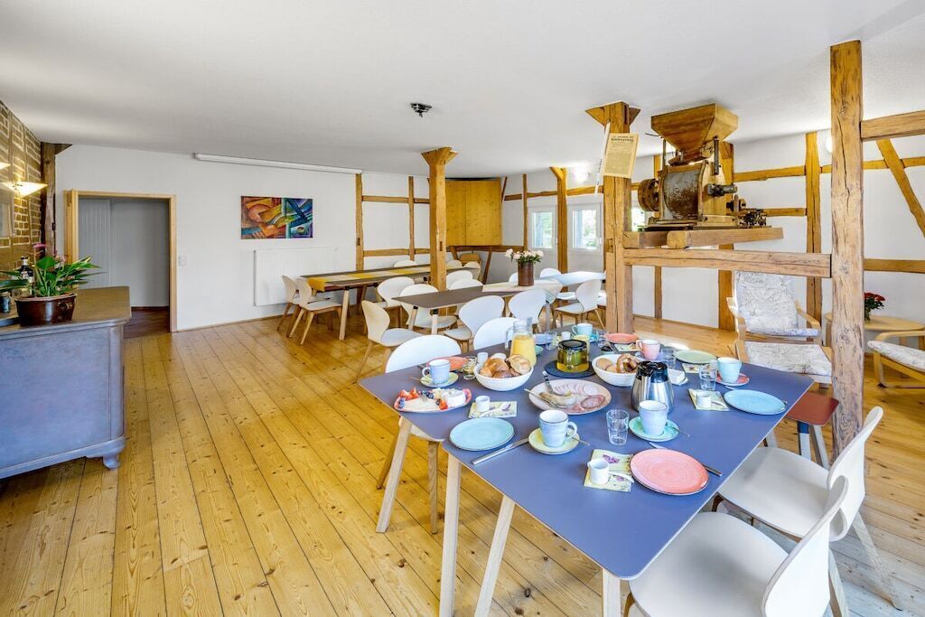 A dining area with a wooden floor, a table set for breakfast, and a rustic coffee machine.