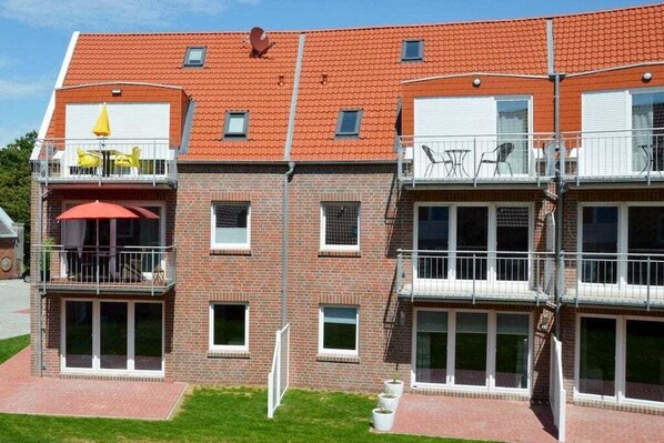 A multi-story residential building with balconies, a brick facade, and a red-tiled roof. - Holiday apartment with 2 bedrooms (Norden-Norddeich)