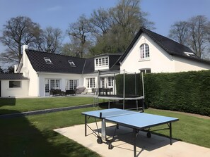 Een woonhuis met een tennisbaan en een tafeltennistafel.
