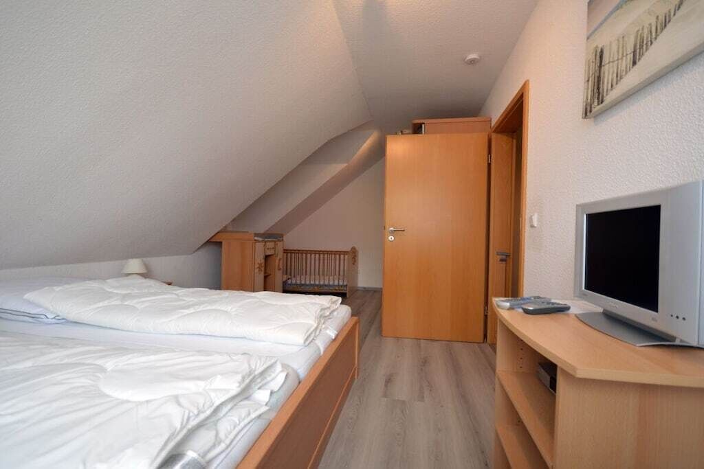 Ein Schlafzimmer mit einem Bett, einem Fernseher und einem Holzschrank.