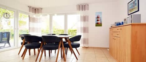 A dining area with a table and chairs, a wooden cabinet, and a view through the window.