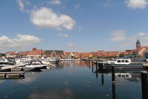 A marina with boats docked, a clear sky, and buildings in the background. - Holiday home with 1 bedroom (Waren (Müritz))
