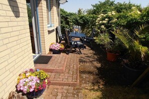 A patio area with a table and chairs, potted plants, and a brick pathway. - Holiday home with 1 bedroom (Waren (Müritz))