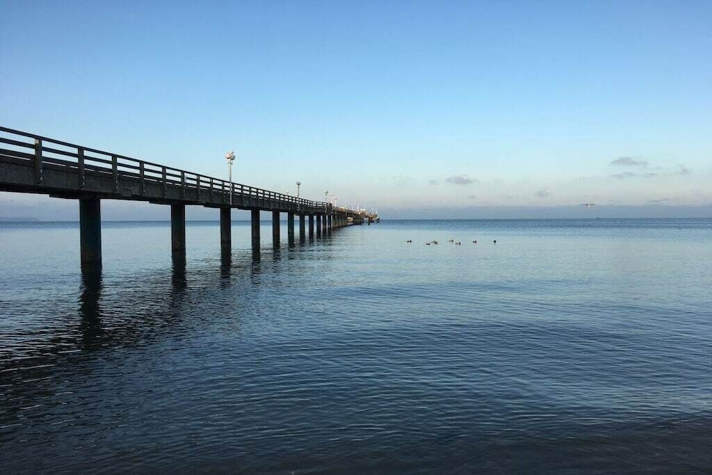 Eine Mole, die sich über ruhiges Wasser erstreckt, mit blauem Himmel darüber.