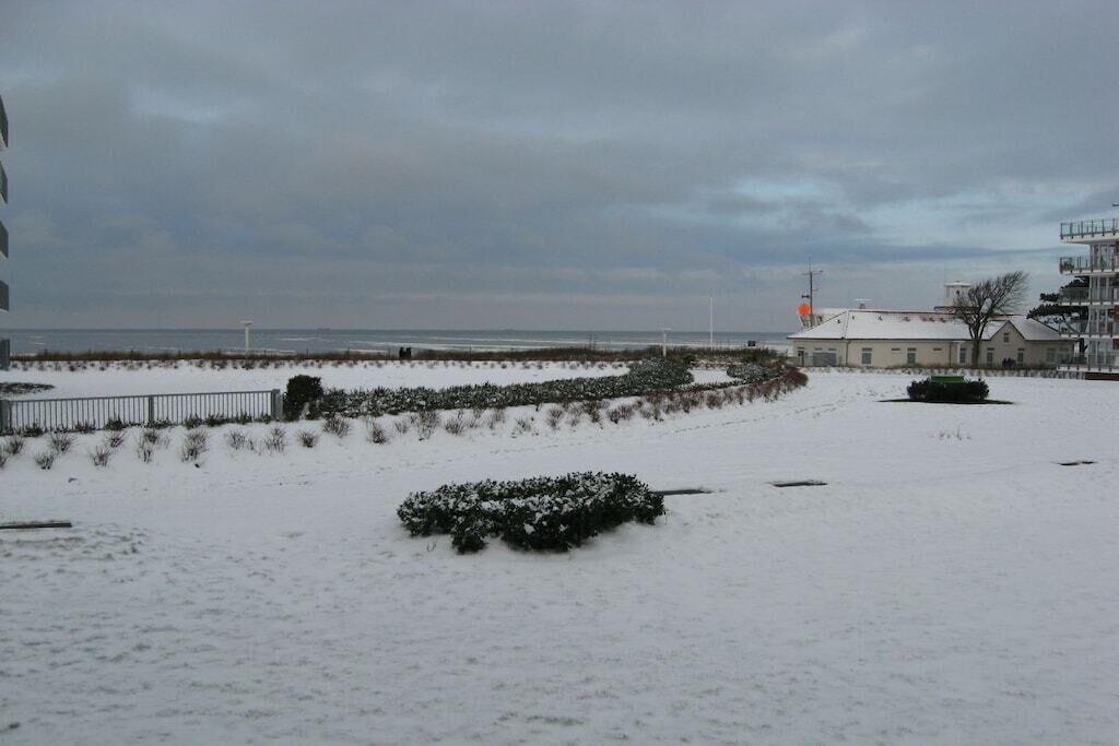 Paesaggio innevato con un edificio e una recinzione in primo piano.