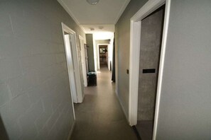 Ein schmaler Gang mit Türen an beiden Seiten, der zu einem Raum mit einem Fenster führt.