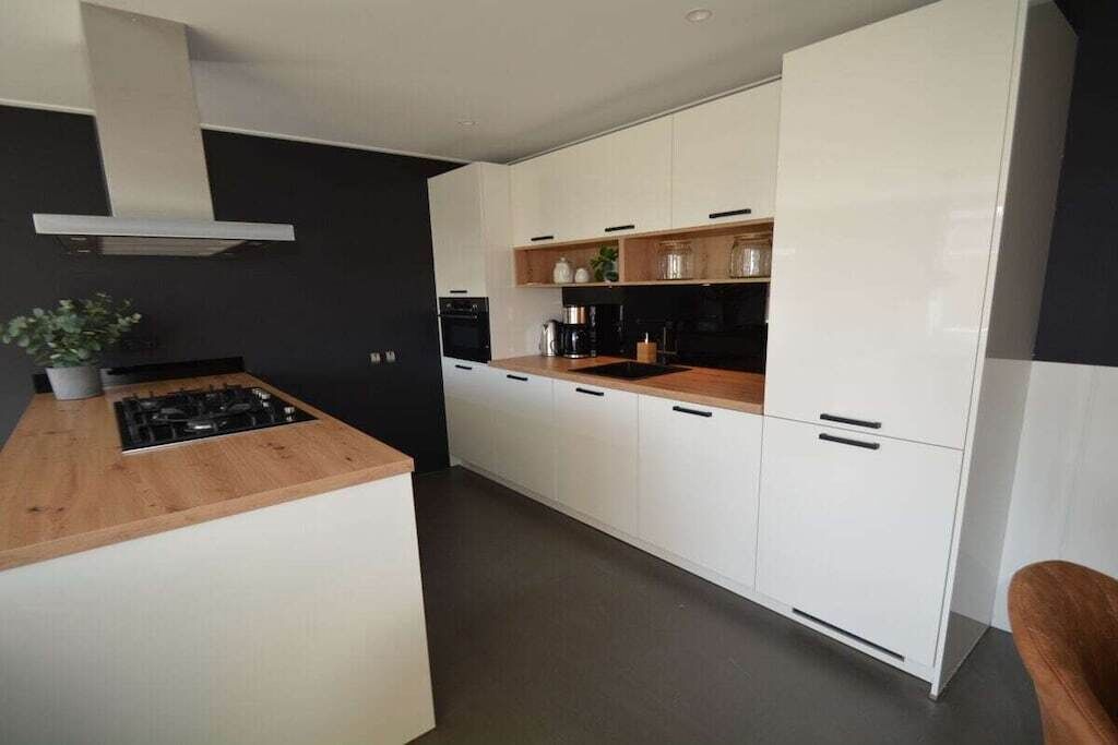 Eine moderne Küche mit weißen Schränken, einer Holz Arbeitsplatte und einem eingebauten Herd.