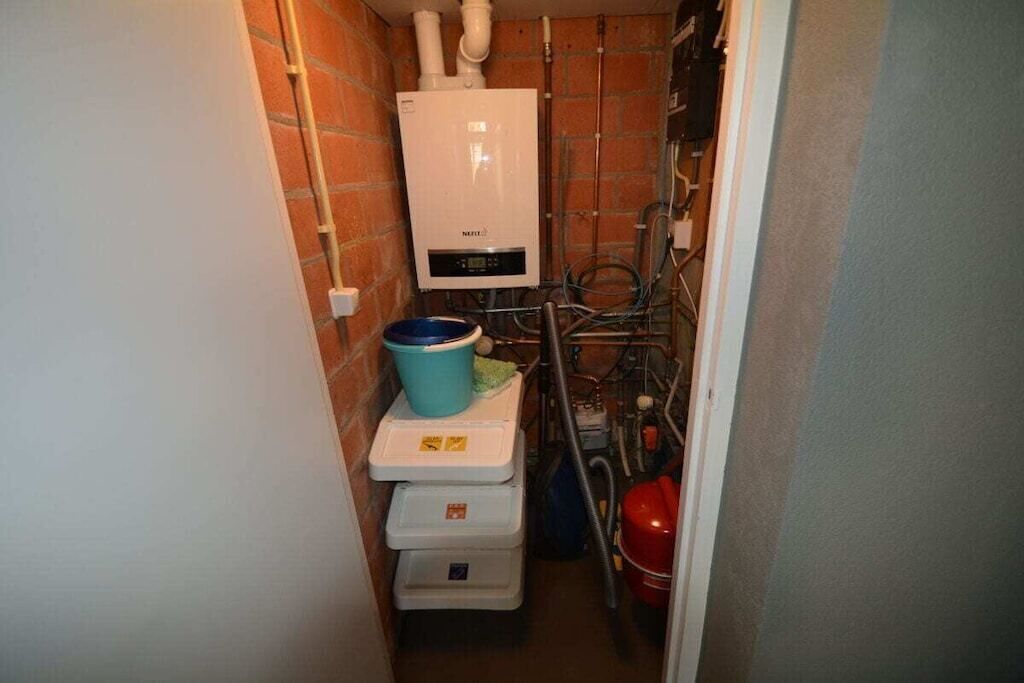 Une petite salle de bain avec un radiateur blanc, un lavabo bleu et un extincteur rouge.