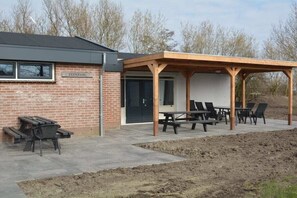 Een gebouw van baksteen met een overdekt terras en picknicktafels.