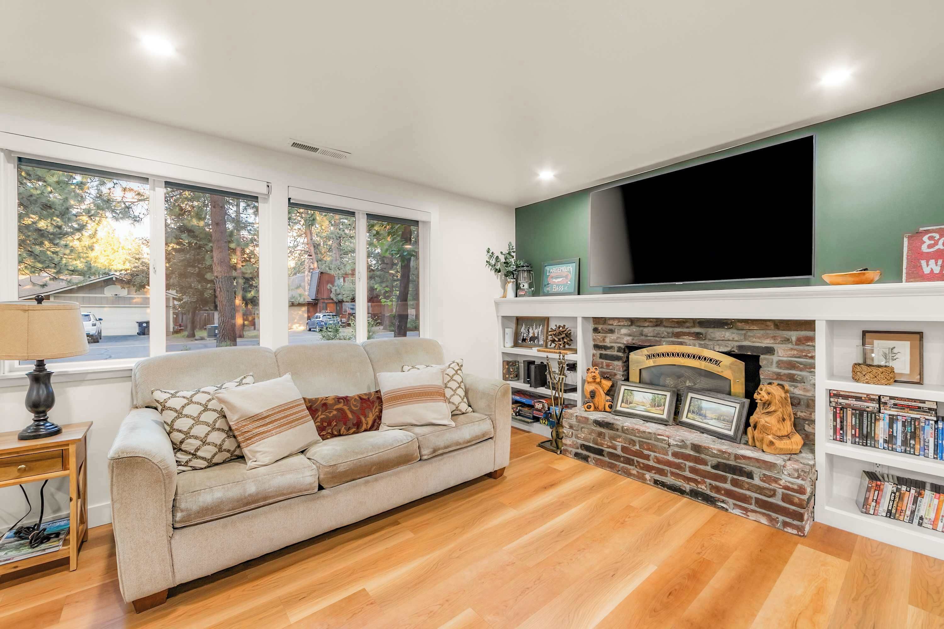 Una sala de estar con sofá, chimenea, estantería y televisor.