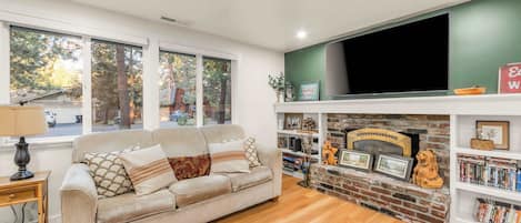 A living room with a sofa, a fireplace, a bookshelf, and a television.
