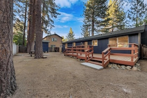 A cabin with a deck and a dirt yard surrounded by trees. - Tanglewood Tahoe Retreat (South Lake Tahoe)
