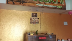 Uma área de recepção com uma placa, um balcão de atendimento e um quadro fixado na parede.