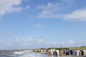 A coastal area with a row of numbered beach huts along the shore. - Holiday home in Hooksiel with swimming pool (Hooksiel)