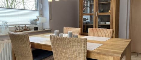 A dining area with a wooden table, wicker chairs, and a cabinet with glass doors.
