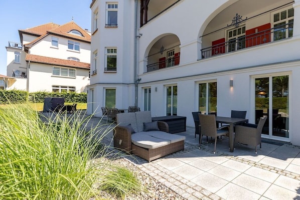 A modern two-story building with a patio area featuring outdoor furniture and a dining set. - Holiday apartment Villa Löwenstein 319577 (Kühlungsborn)