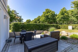 An outdoor patio area with a table and chairs, surrounded by a hedge and trees. - Holiday apartment Villa Löwenstein 319577 (Kühlungsborn)