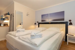 A hotel room with a bed, a bedside table, a lamp, a mirror, and a wall with two framed pictures. - Holiday apartment Villa Löwenstein 319577 (Kühlungsborn)