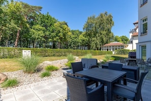 An outdoor patio area with a table and chairs, surrounded by a hedge and trees. - Holiday apartment Villa Löwenstein 319577 (Kühlungsborn)