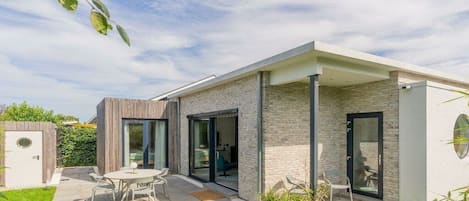 A modern house with a patio, a dining area, and a garage.
