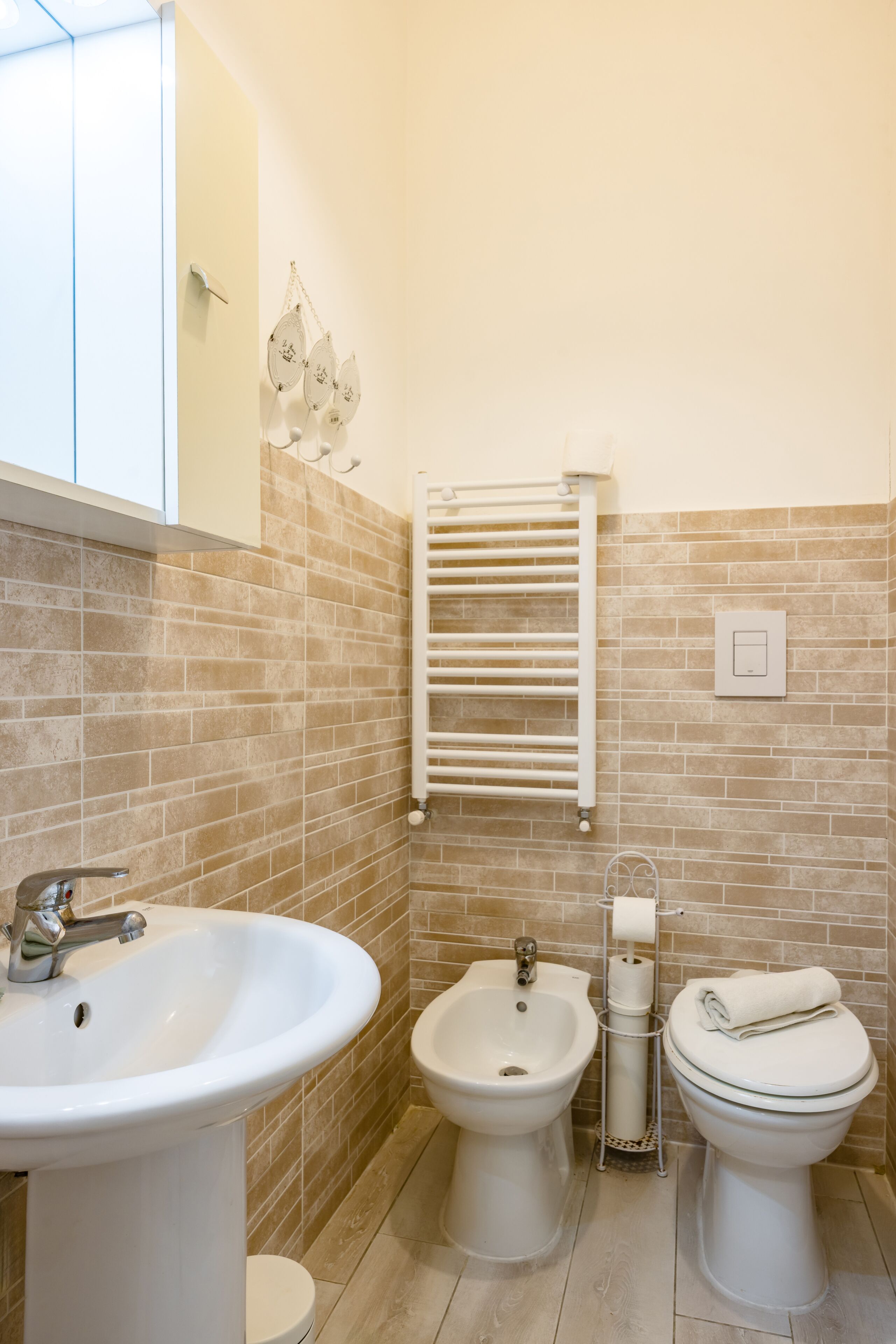 A bathroom with a sink, bidet, toilet, and towel rack.