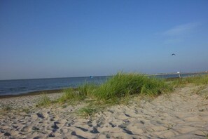 A sandy beach with a clear sky and a distant pier. - Holiday home in Hooksiel with swimming pool (Hooksiel)