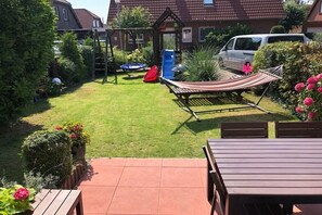 A backyard with a hammock, a slide, and a play structure. - Holiday home in Hooksiel with swimming pool (Hooksiel)