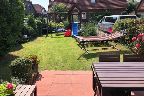 Ein Garten mit einer Hängematte, einer Rutsche und einer Spielanlage.
