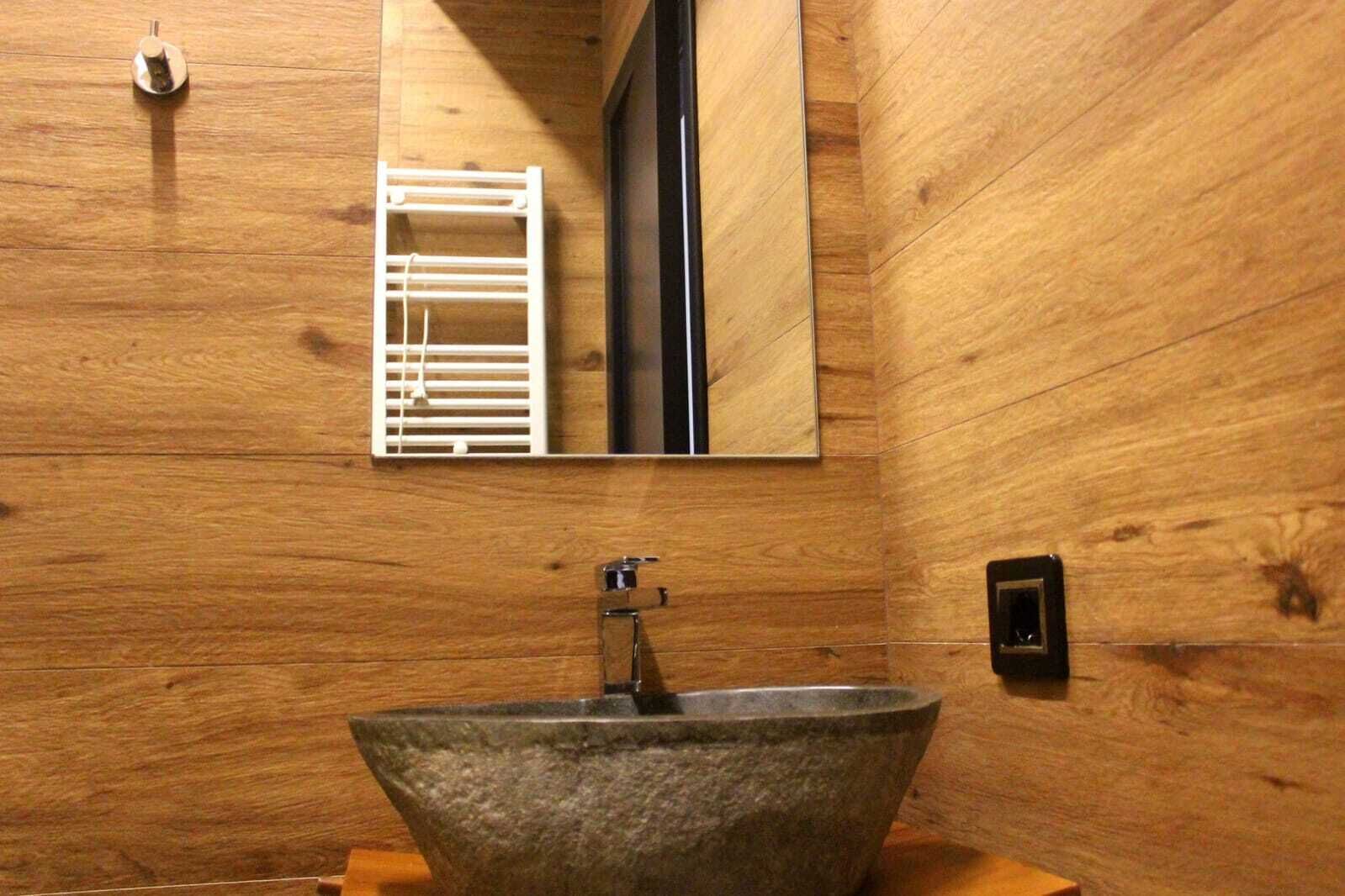 Un baño con un lavamanos de piedra, un espejo y un perchero para toallas.
