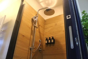 Une cabine de douche en bois équipée d’un pommeau de douche à main et d’un robinet fixé au mur.