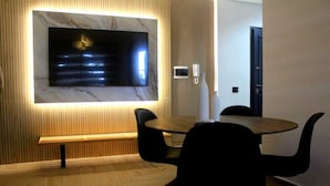 Un comedor moderno con pared de mármol, un televisor de pantalla plana y un banco.
