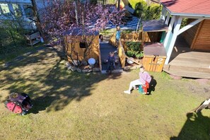 A wooden playhouse with a slide, surrounded by grass and trees. - Holiday apartment with 2 bedrooms (Kölpinsee \/ Loddin)