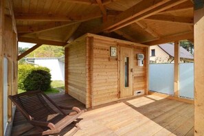 A wooden cabin with a porch, a bench, and a door with a window. - Holiday apartment with 2 bedrooms (Kölpinsee \/ Loddin)