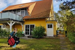 A yellow house with a red-tiled roof, a balcony, and a front door. - Holiday apartment with 2 bedrooms (Kölpinsee \/ Loddin)