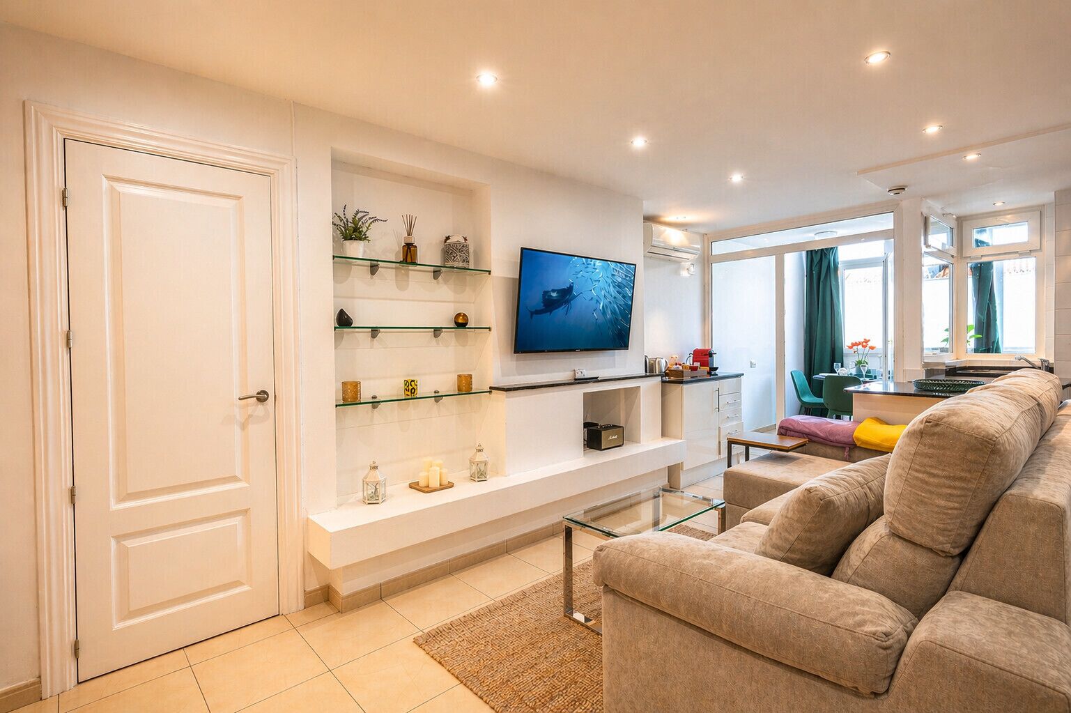 A modern living room with a sofa, TV, and shelves with decorative items.