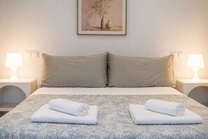 A neatly made bed with two pillows, two rolled towels, and a framed picture on the wall. - Nogalera Privée - Adults Only (Torremolinos)